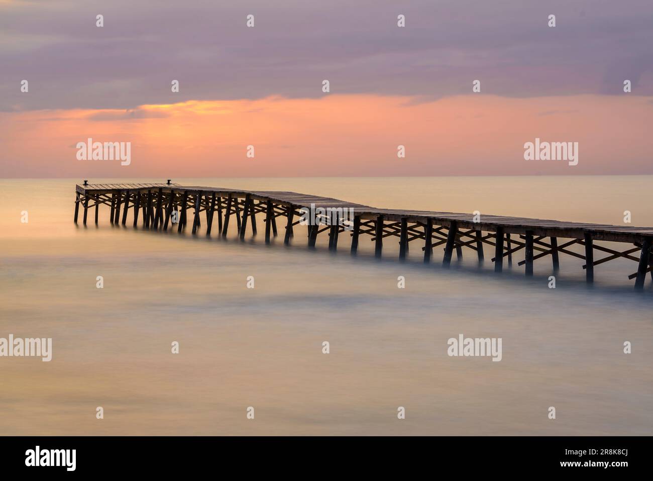 Sommersonnenaufgang auf einem hölzernen Pier an einem Strand in Platja de Muro (Mallorca, Balearen, Spanien) ESP: Amanecer veraniego en un muelle de madera en Muro Stockfoto