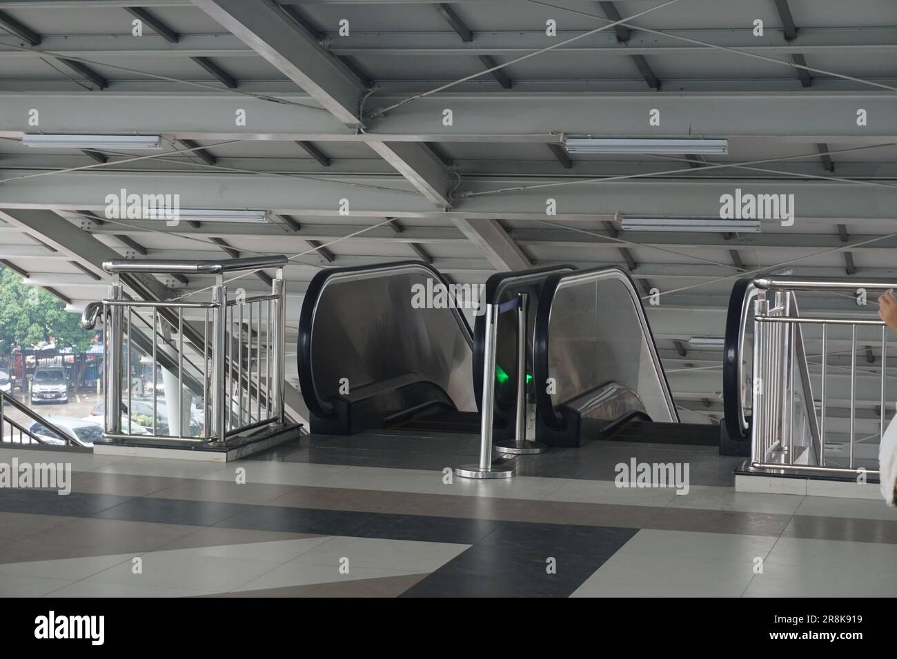 Sie können sehen, wie der Sicherheitsdienst den Zugpassagieren in der Nähe der Rolltreppe Anweisungen gibt, mit einer geschäftigen Atmosphäre Stockfoto