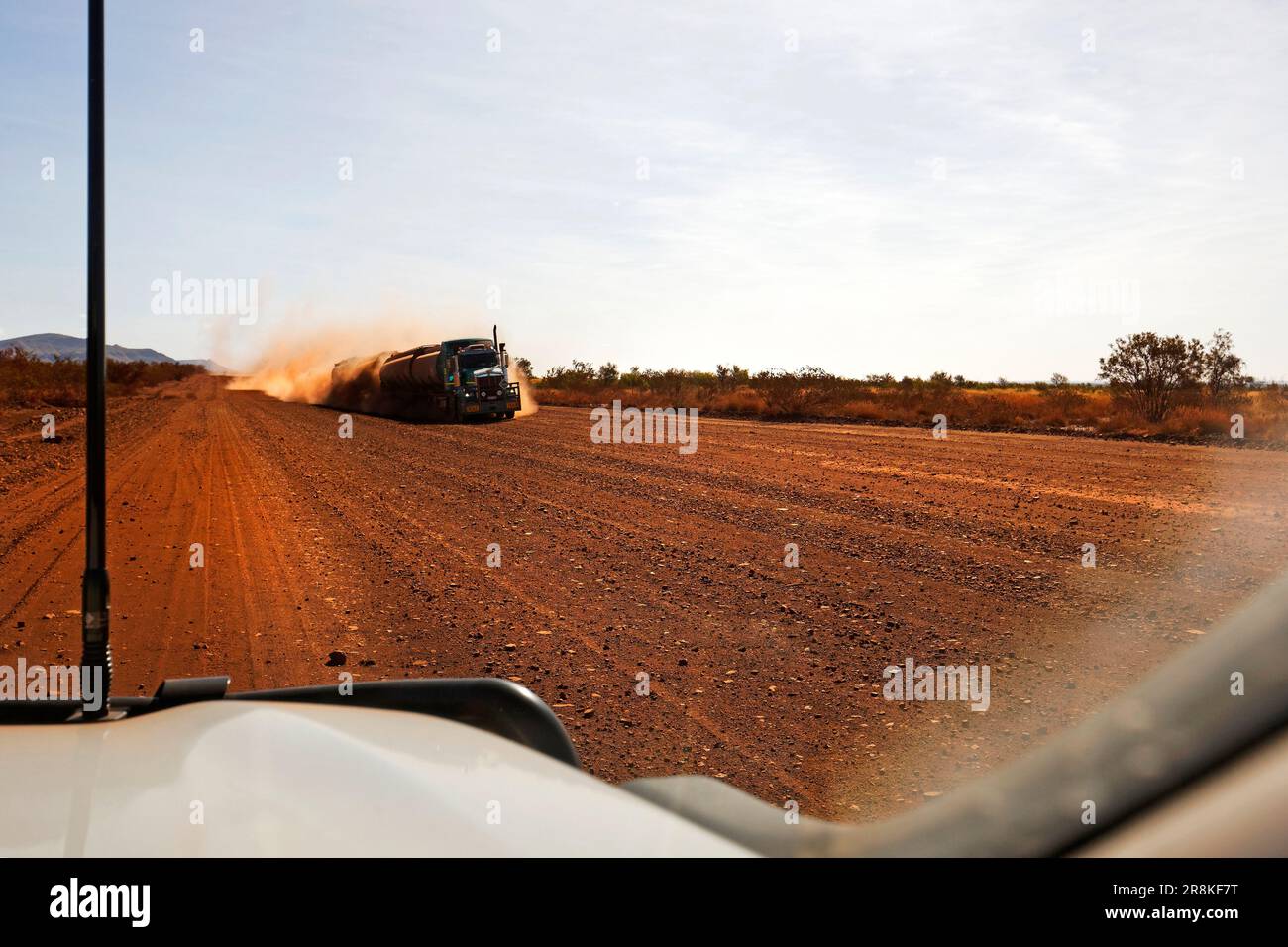 Ein großer Lastwagen nähert sich einem Auto auf einer roten Feldstraße, Pilbara, Westaustralien Stockfoto