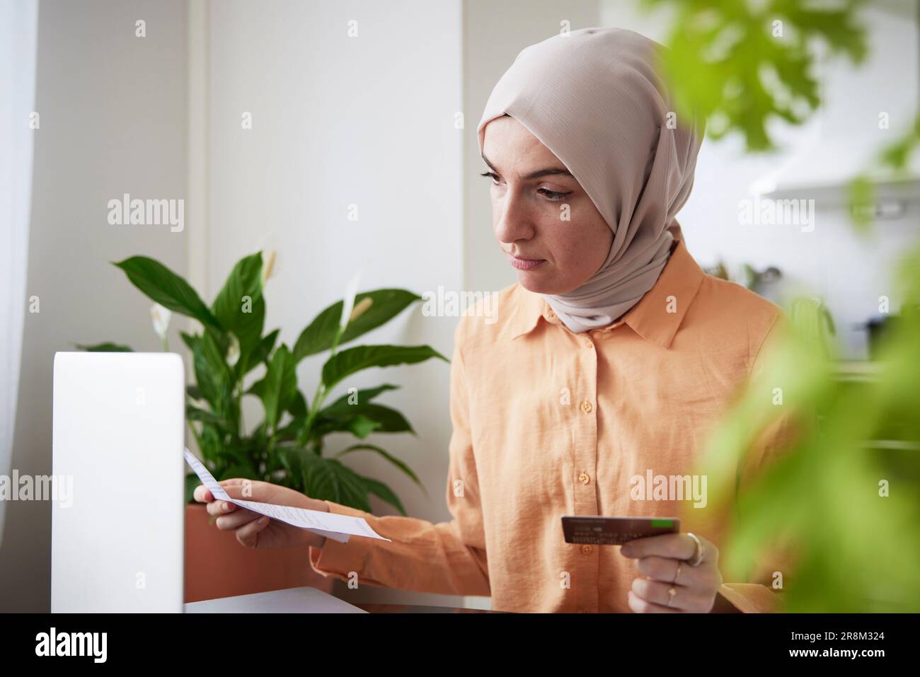 Lächelnde Frau mit Hijab und Kreditkarte beim Online-Shopping Stockfoto
