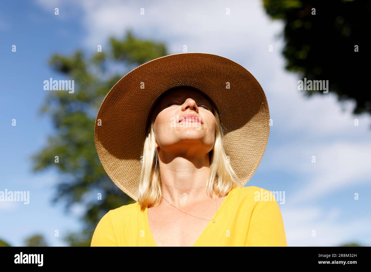 Lächelnde Frau, die sich im Sonnenlicht entspannt Stockfoto