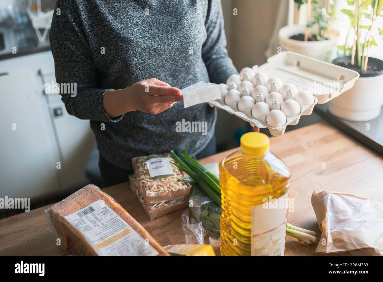 Frau, die während der Inflation mit steigenden Preisen für Lebensmittel und Konsumgüter die Quittungen aus dem Supermarkt überprüft Stockfoto