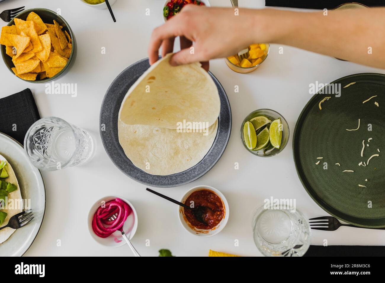 Person, die während des mexikanischen Festes Tortilla aus dem Stapel nimmt Stockfoto