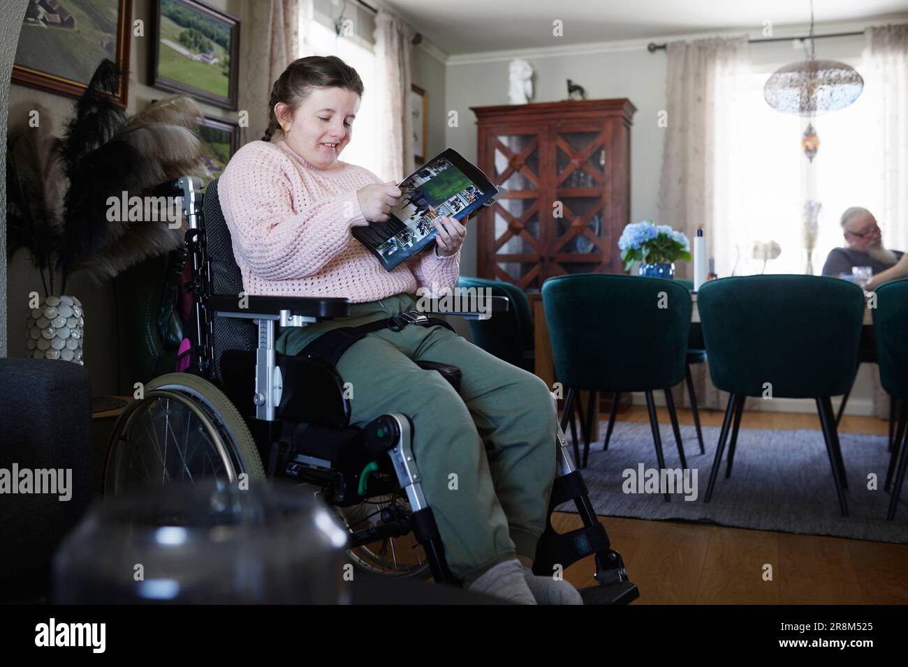 Behindertes Teenager-Mädchen liest Zeitschrift im Wohnzimmer Stockfoto