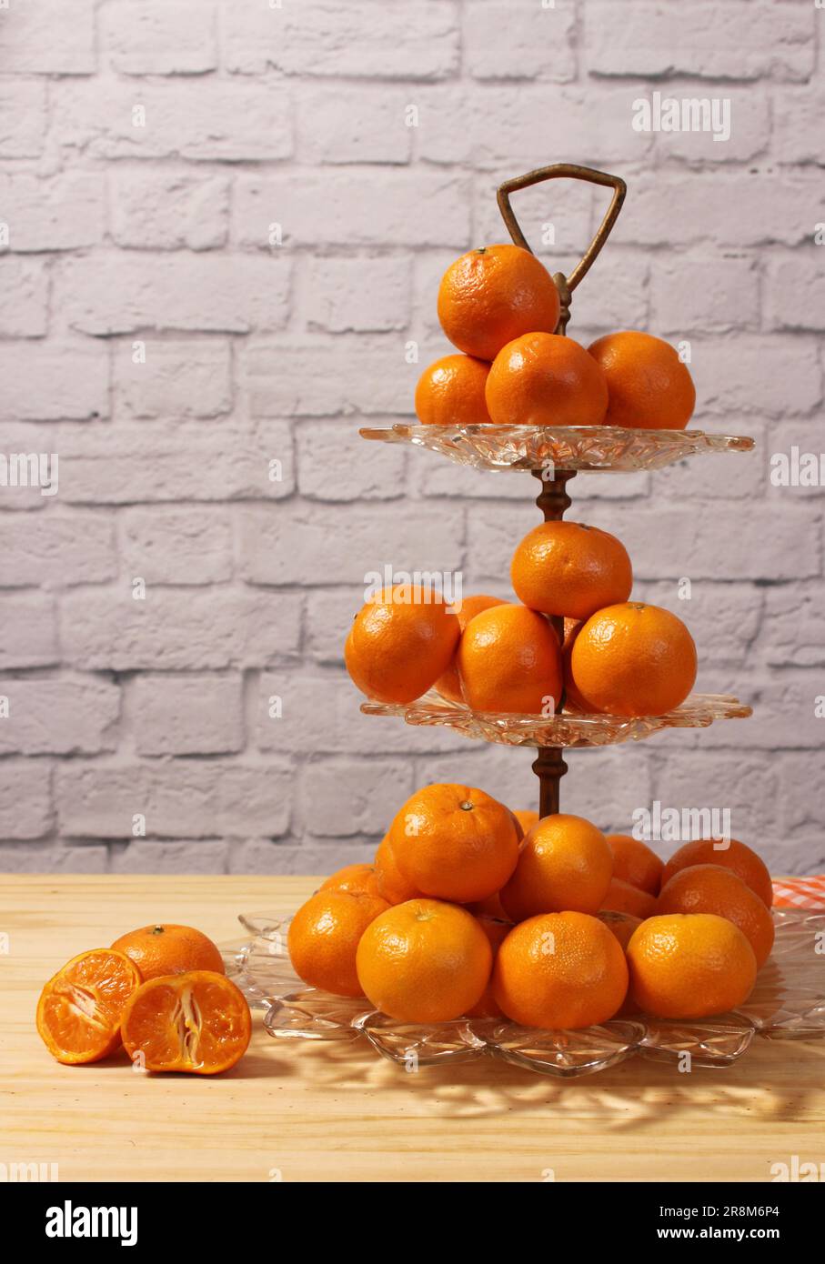 Antike Kristallschale Mit Kleinen Orangen. Dessert mit Backsteinwand im Hintergrund Stockfoto