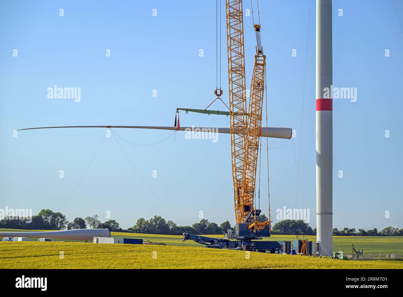 Windturbinenbaustelle, Kran hebt eine Schaufel an, um sie auf dem Turm zu installieren, Schwerindustrie für Strom, erneuerbare Energien und Strom, rur Stockfoto