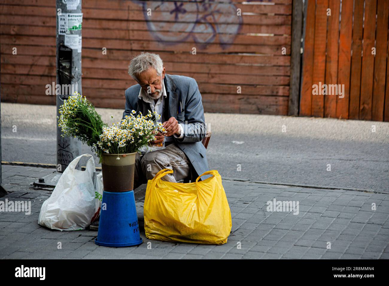 Ukrainischer Rentner mit würde verkauft Blumen als Ergänzung zu seiner bescheidenen Pension an einem schönen Maiabend in der Innenstadt der südlichen Stadt Dnepr Stockfoto