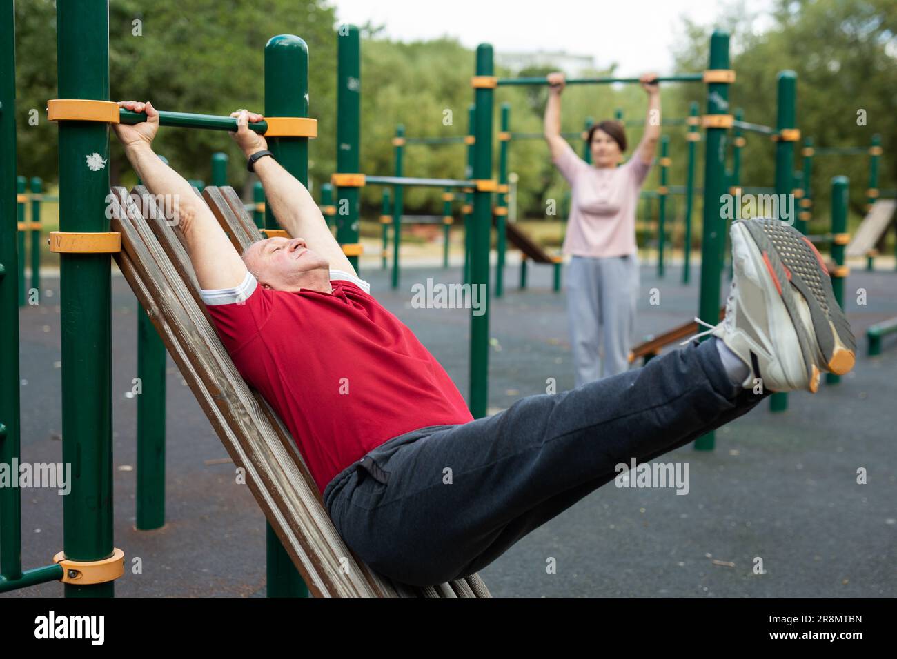 Ein älterer Mann geht in den Stadtpark auf dem Sportgelände und macht