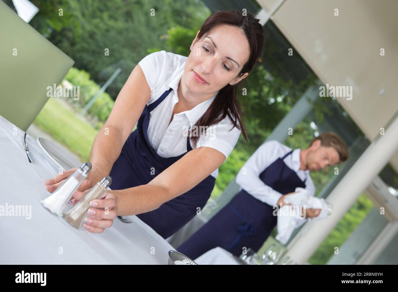 Lächelnde Kellnerin, die den Tisch deckt Stockfoto