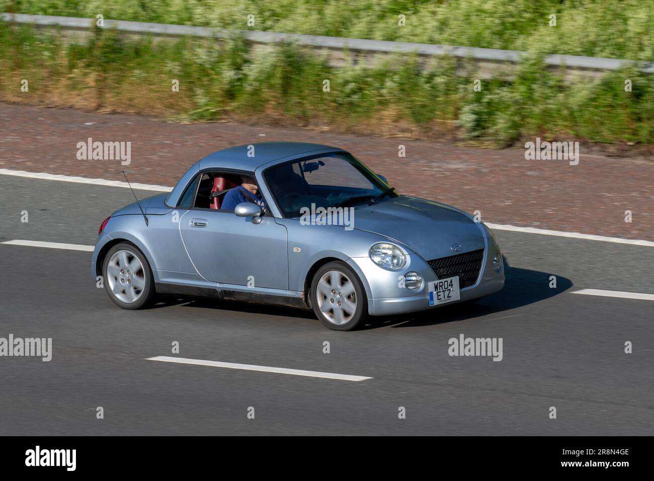 2004 Daihatsu Copen, flippiges kleines Cabrio, 2-türiges Kei-Auto mit Metallfaltdach, auf der Autobahn M6 im Großraum Manchester, Großbritannien Stockfoto