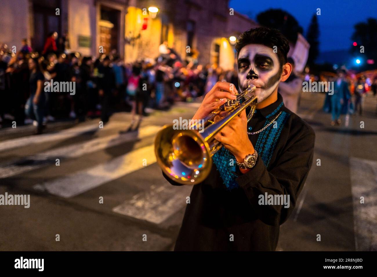 Ein mexikanischer Musiker, der Catrin-Gesichtsfarbe trägt, spielt die Trompete während der Feierlichkeiten zum Todestag in Morelia, Michoacán, Mexiko. Stockfoto