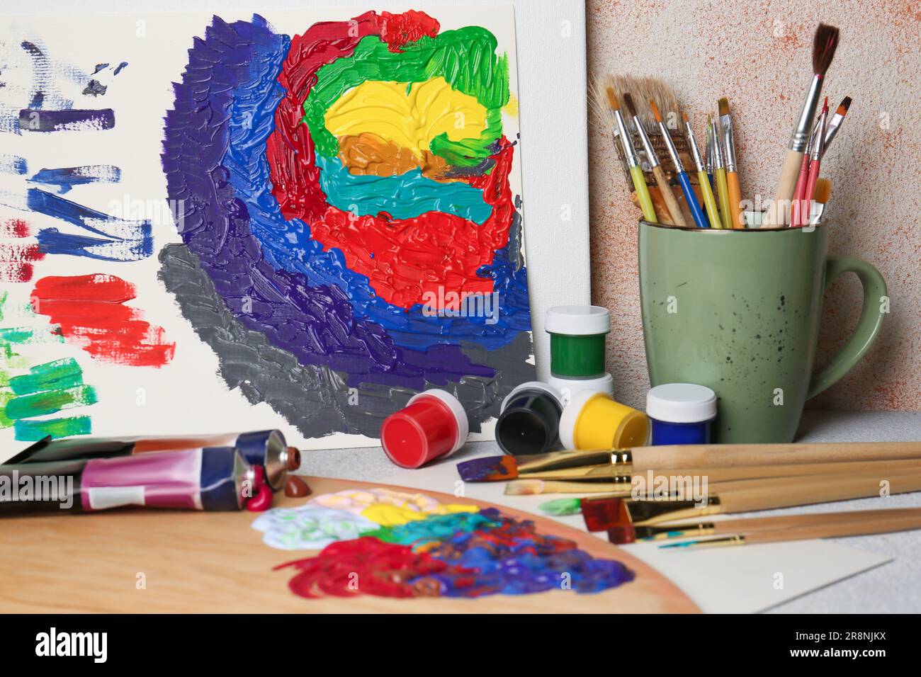 Abstraktes farbenfrohes Malen und Werkzeuge verschiedener Künstler auf einem strukturierten Tisch Stockfoto