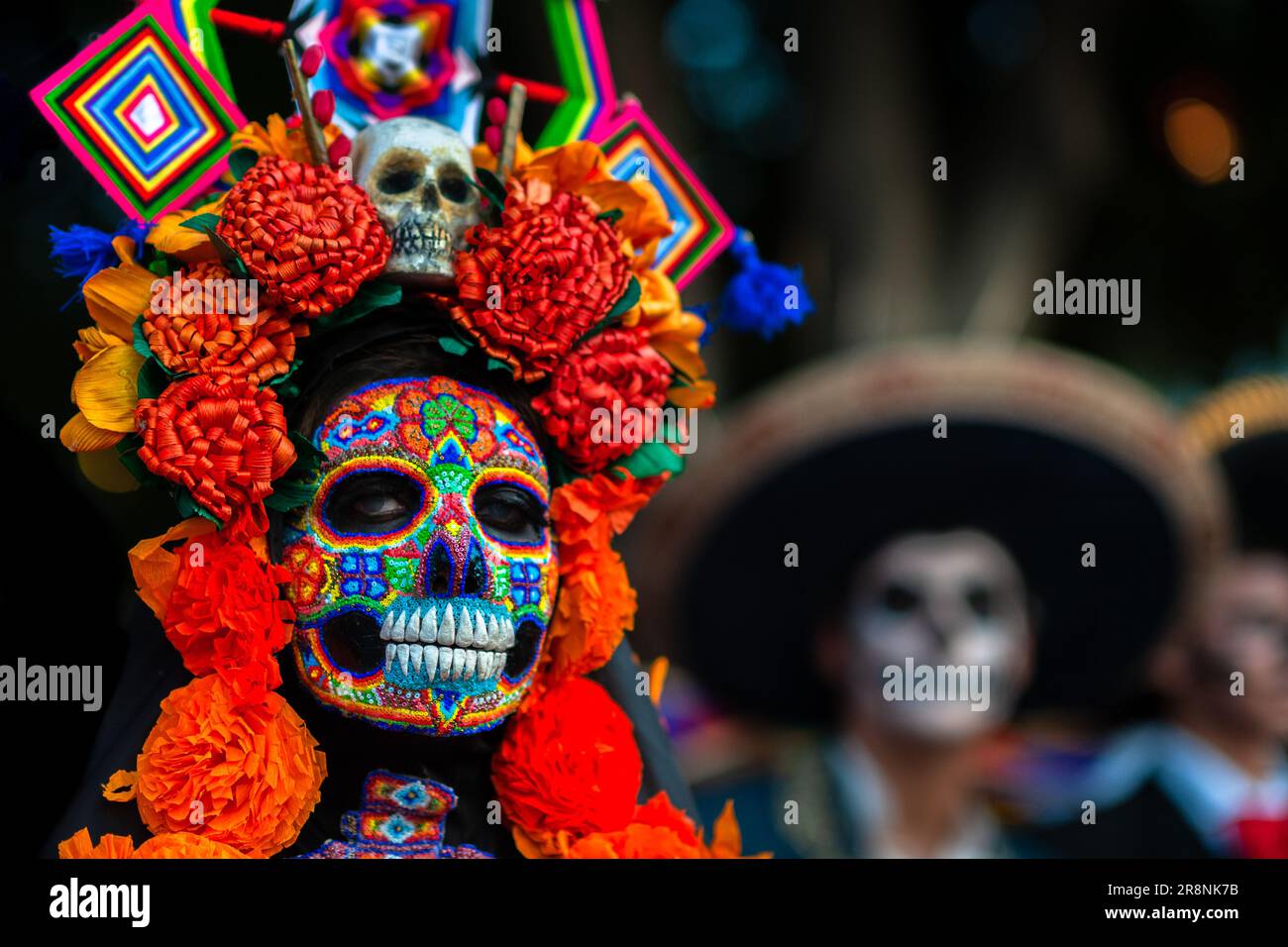 Eine Mexikanerin, die als La Catrina verkleidet ist und eine Perlenmaske von Huichol trägt, nimmt an den Feierlichkeiten zum Todestag in Morelia, Michoacán, Mexiko Teil. Stockfoto