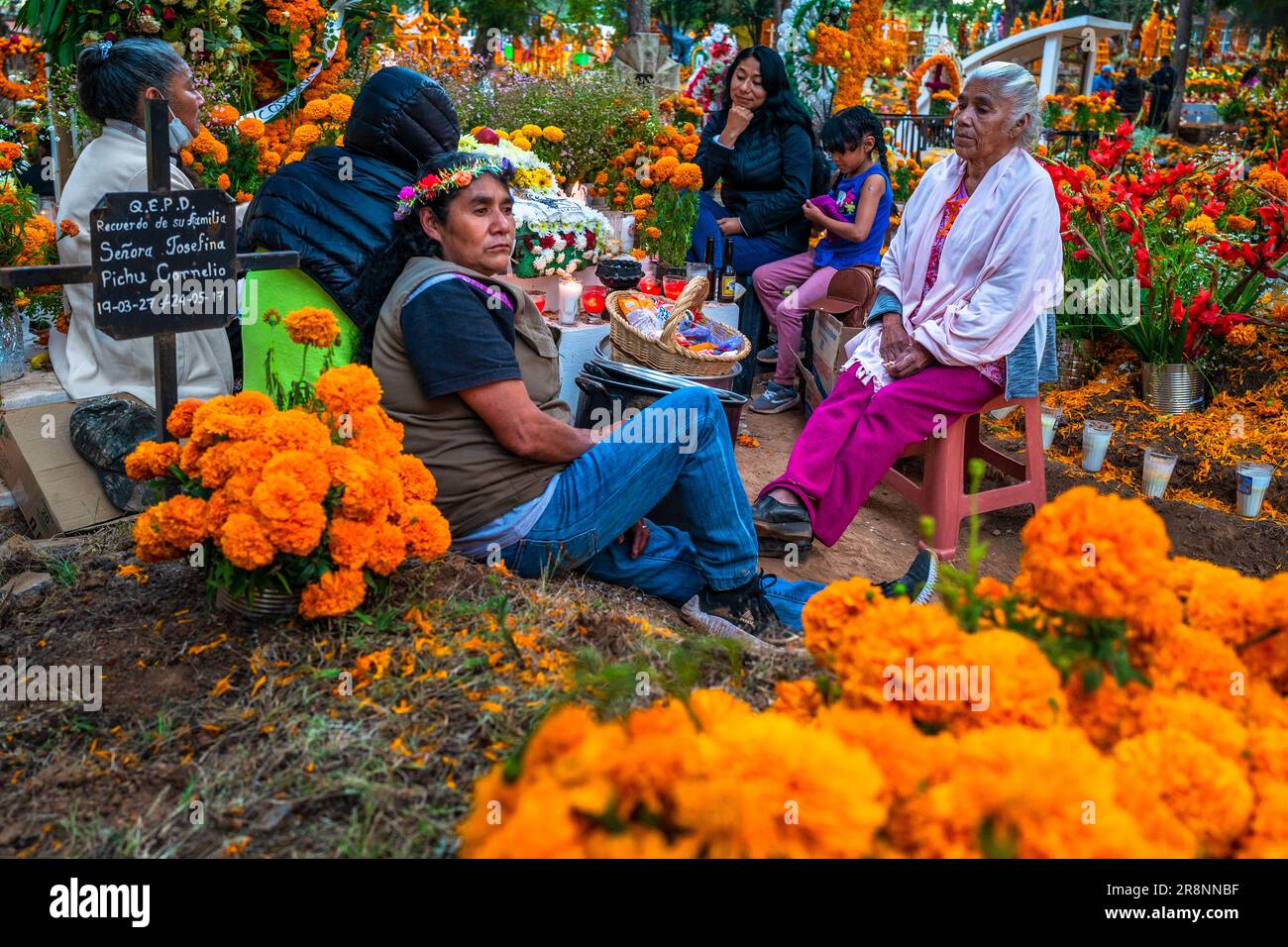 Während der Feierlichkeiten zum Todestag in Tzintzuntzan, Mexiko, sitzen einheimische mexikanische Frauen aus einer Familie inmitten der Gräber auf einem Friedhof. Stockfoto