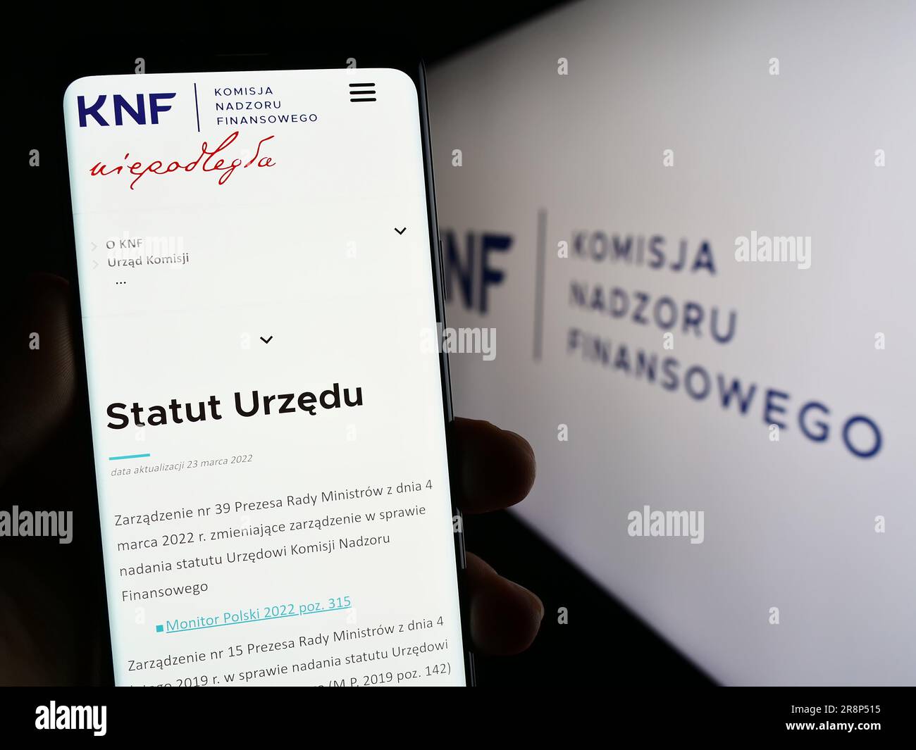 Person, die ein Smartphone mit der Webseite der Behörde Komisja Nadzoru Finansowego (KNF) auf dem Bildschirm mit Logo hält. Konzentrieren Sie sich auf die Mitte des Telefondisplays. Stockfoto
