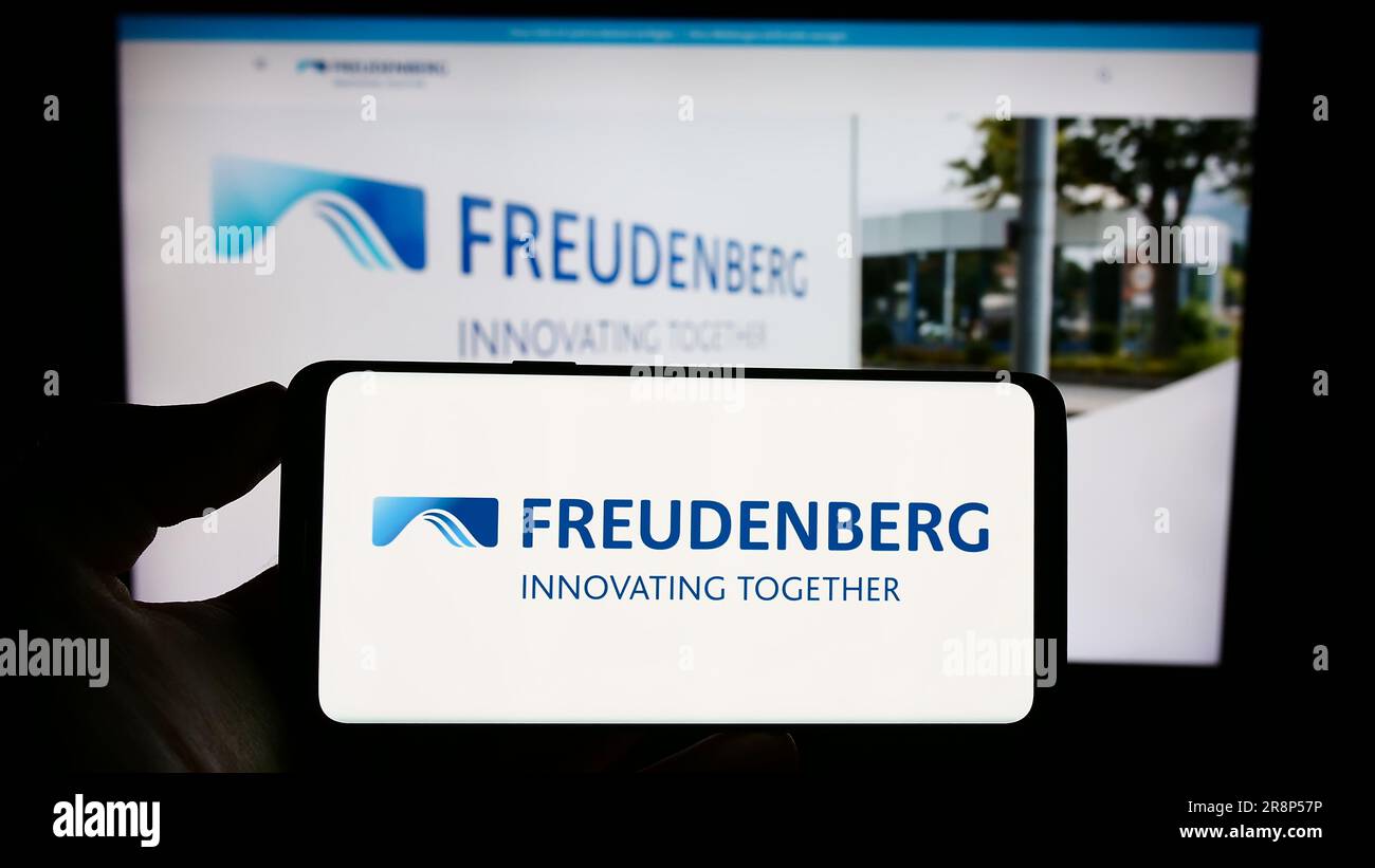 Person, die ein Mobiltelefon mit dem Logo des deutschen Unternehmens Freudenberg SE auf dem Bildschirm vor der geschäftlichen Webseite hält. Konzentrieren Sie sich auf das Display des Telefons. Stockfoto