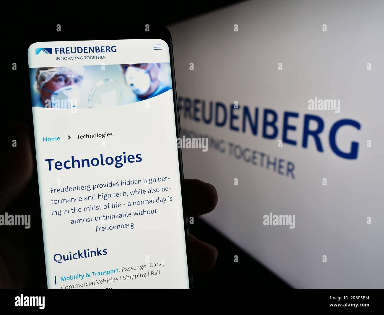 Person, die ein Mobiltelefon mit einer Webseite des deutschen Unternehmens Freudenberg SE auf dem Bildschirm vor dem Logo hält. Konzentrieren Sie sich auf die Mitte des Telefondisplays. Stockfoto
