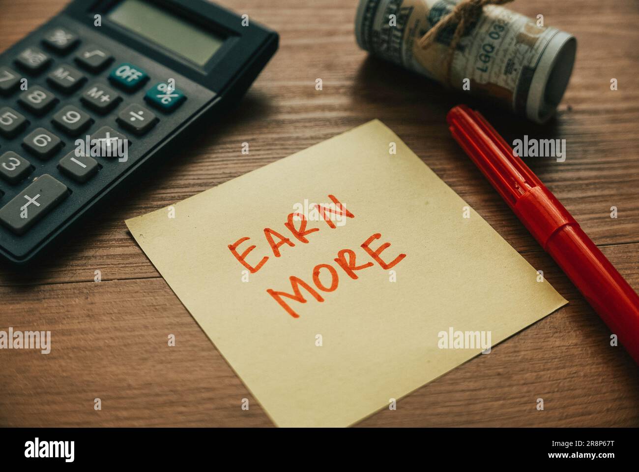 Selektiver Fokus auf Taschenrechner, Geldschreiber und Papier, geschrieben mit Earn More. Stockfoto