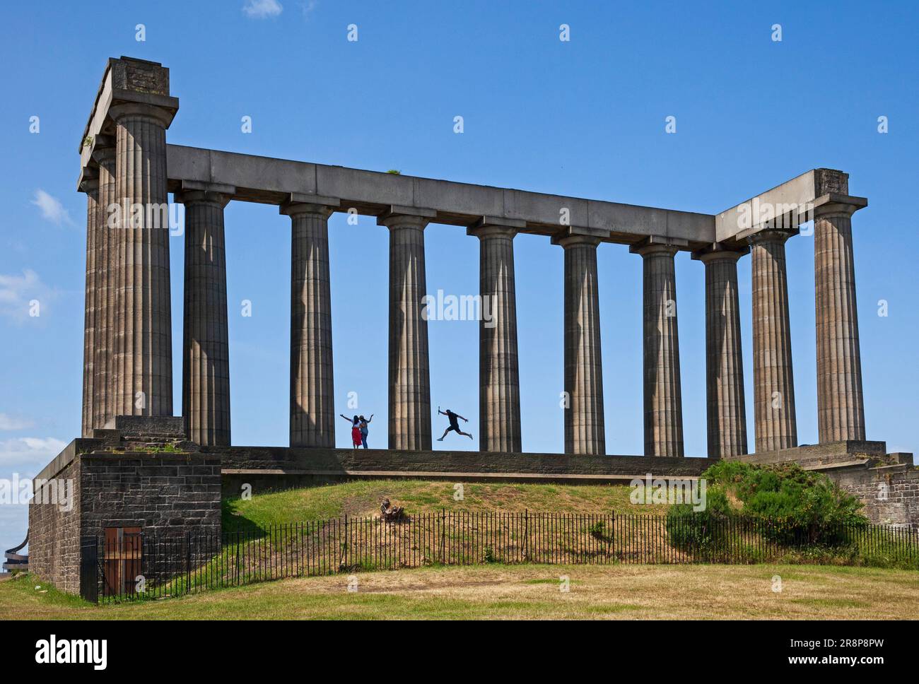 National Monument, Calton Hill, Edinburgh, Schottland, Großbritannien. 22. Juni 2023 Ein Tourist wurde dabei erwischt, wie er in die Luft sprang, während sein Partner ein Foto von dem Moment machte. Die meisten Touristen, die Calton Hill besuchen, steigen hinauf, um auf dem historischen Gebäude fotografiert zu werden. Das National Monument of Scotland ist Schottlands nationales Denkmal für schottische Soldaten und Matrosen, die in den napoleonischen Kriegen starben. Laut Inschrift sollte es „ein Denkmal der Vergangenheit und Anreiz für den zukünftigen Heldentum der Männer von Schottland“ sein Kredit: Arch White/alamy Live News. Stockfoto