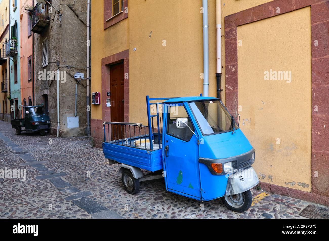 BOSA, ITALIEN - 28. MAI 2023: Bizarre, für Italien typische dreirädrige Piaggio-Mini-Trucks, die in der Stadt Bosa auf der Insel Sardinien geparkt werden. Stockfoto