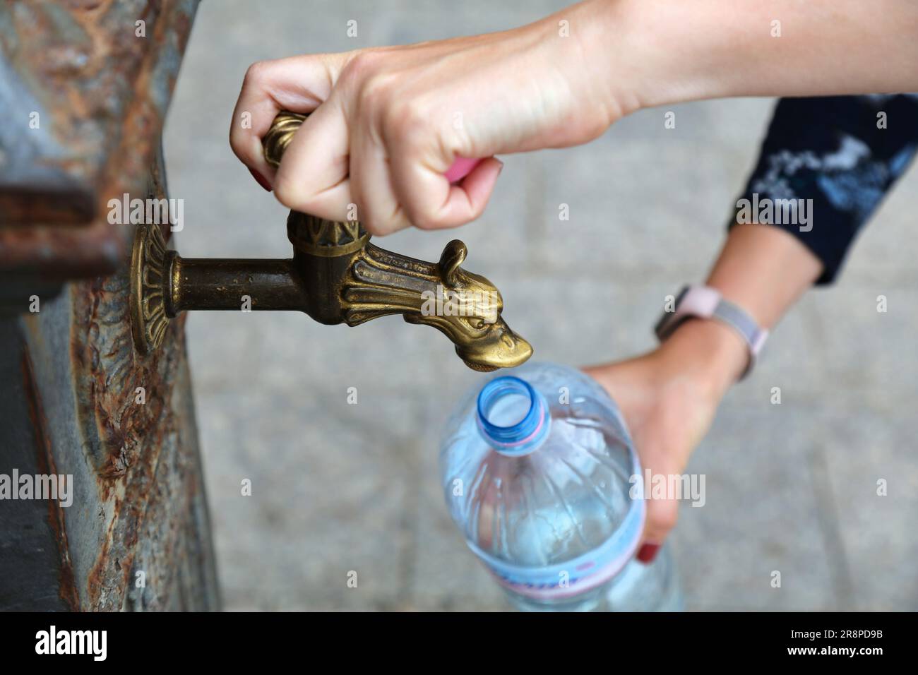Nachfüllflasche aus Kunststoff für Haustiere aus dem öffentlichen Wasserhahn in Alghero, Italien. Kommunaler Trinkwasserhahn - nachhaltiger Tourismus. Stockfoto