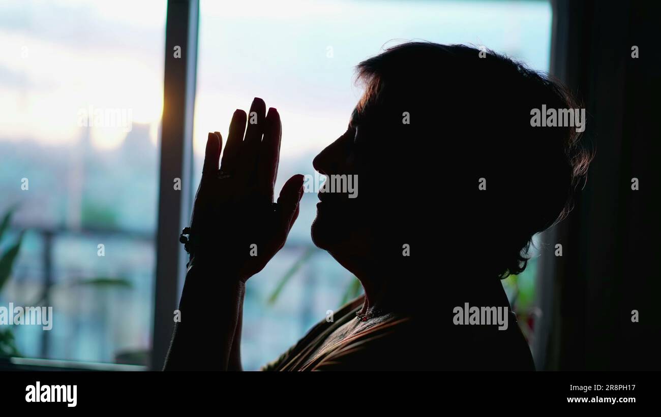 Silhouette einer Seniorin im Gebet bei sonnenuntergang in hoem. Der  nachdenkliche meditative Seniorenmensch betet zu Gott Stockfotografie -  Alamy