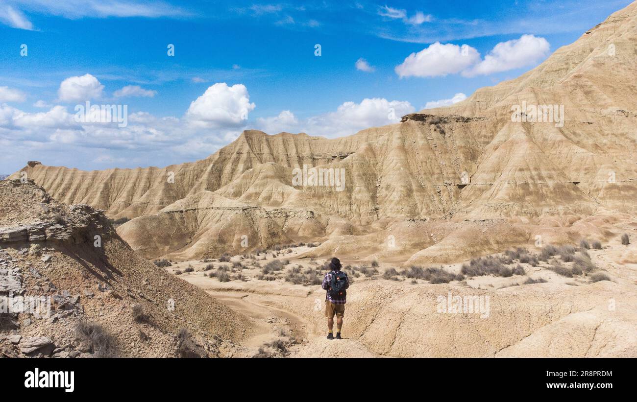 Panoramablick auf die bunte Steinwüste und der Reisende auf dem Rücken wandert auf den Felsen Stockfoto