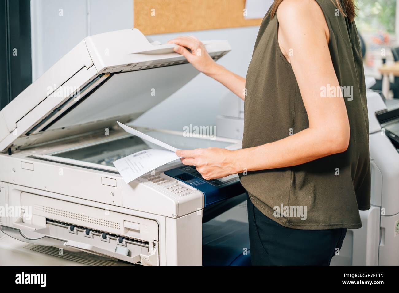Vertrauensvolle Sekretärin, die mit modernen Druckern arbeitet und im Unternehmen arbeitet Stockfoto