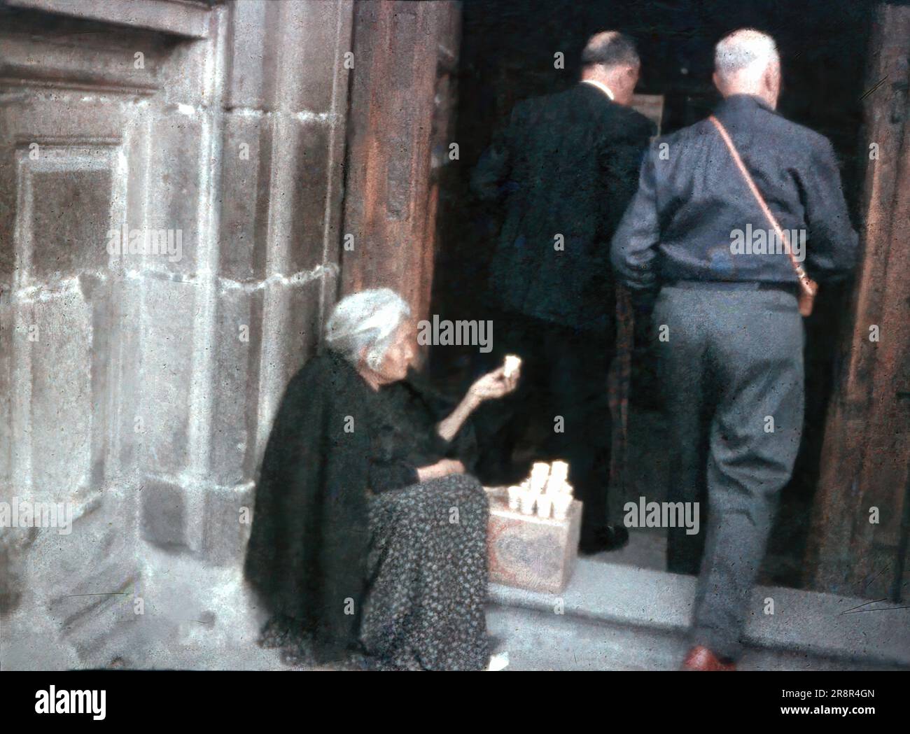 Eine alte Frau verkauft Kerzen am Eingang einer Kirche - 1950er Italien, klassischer 8-mm-Minox-Diafilm. Stockfoto