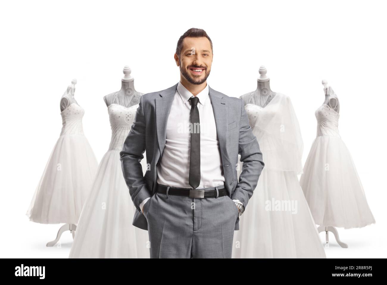 Professioneller Mann in einem grauen Anzug, der vor Hochzeitskleidern steht, isoliert auf weißem Hintergrund Stockfoto