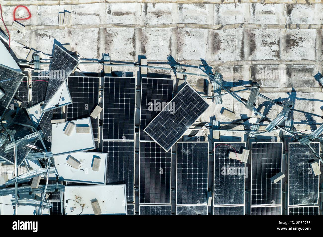 Draufsicht der durch den Hurrikan Ian zerstörten Photovoltaik-Solarpaneele, die auf dem Dach des Industriebaues zur Erzeugung von ökologischem Strom montiert sind Stockfoto