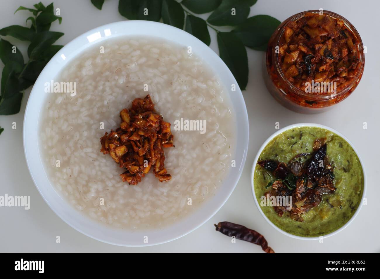 Kanji und Kadumanga. Reismehl mit Kerala Matta Reis. Serviert mit rohem Bananencurry und Kerala-Mango-Gurke. Auf einem weißen Hintern geschossen Stockfoto