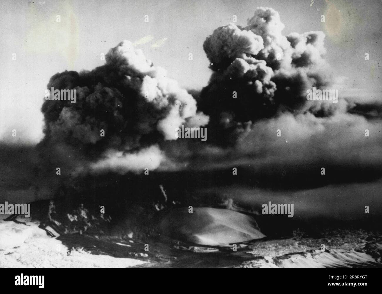 Hekla bricht nach 100 Jahren aus -- große, aufwirbelnde Rauchwolken über Hekla. Ein Lavastrom fließt in den linken Vordergrund. Nach mehr als hundert Jahren Stille brach der isländische Vulkan Hekla mit einer Explosion aus, die eine Säule aus Steinen, Lava und Rauch fast sechs Meilen über dem 5.500 Meter hohen Gipfel auslöste. Die durch den Ausbruch verursachte Erdrebe wurde in Reykjavik, der Hauptstadt, 90 Meilen nordöstlich gespürt. Chester Kronfelt, Fotograf von American Overseas Airlines, der zum Vulkan geflogen ist, um dieses Bild zu machen, sagt, dass, wenn sich das Flugzeug dem Vulkan nähert, die Turbulenzen ca.… Stockfoto