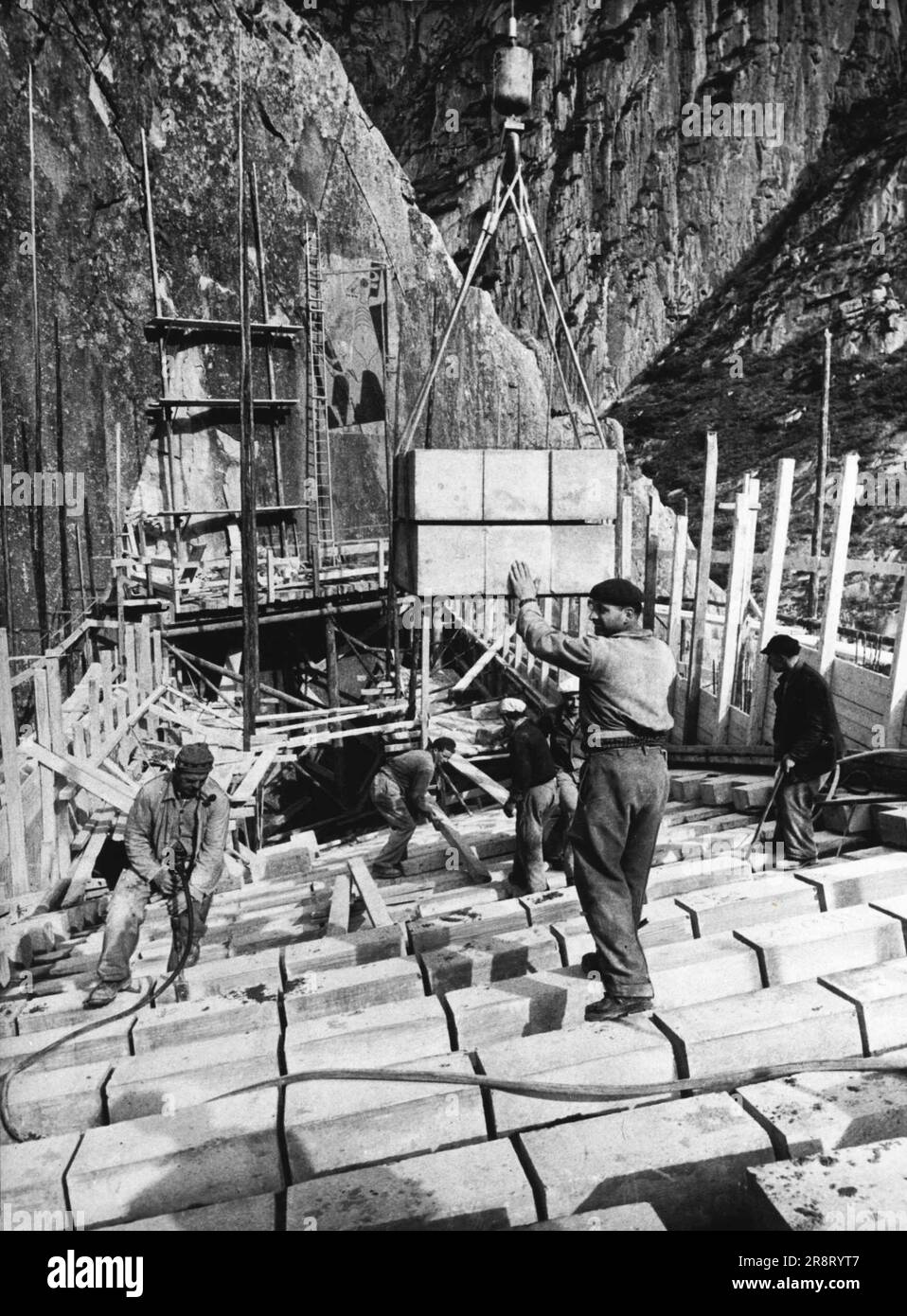 Die neue "Teufelsbrücke" auf der St. Gotthard-Pass in den Alpen -- Eine neue Straßenbrücke über die Schollenen-Schlucht auf der St. Der Gotthard Pass befindet sich derzeit im Bau. In den letzten Jahren hat sich gezeigt, dass die bestehende, 1828 errichtete Brücke nicht mehr der Belastung des ständig wachsenden Verkehrsflusses in die Schweiz standhalten konnte. Die Schweizer Ingenieure erwarten, dass die neue Brücke, die im Frühjahr begonnen wurde, vor dem kommenden Winter fertiggestellt wird. Dieses Foto zeigt die Granit- und Betonblöcke, die an den vorgeschriebenen Stellen verlegt werden. Zum Schweißen wird ein spezieller Mörteltyp verwendet… Stockfoto