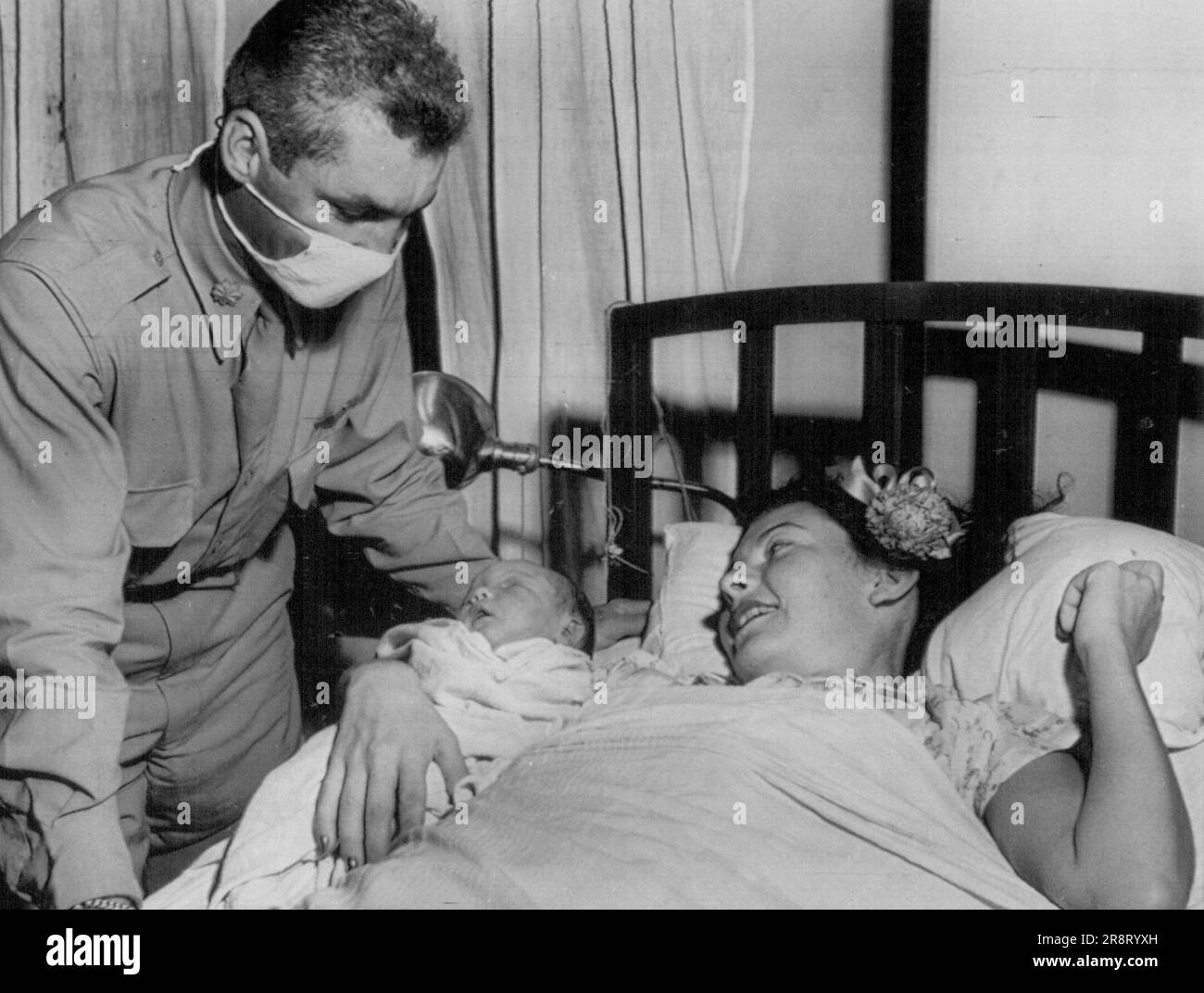 Major Swancutt sieht Son, Major W.P. Swancutt, Pilot der Operation Crossroads, maskiert zum Schutz des Babys, und Mr. Swancutt sehen zum ersten Mal zusammen nach ihrem Sohn Woodrow, Junior 13. Juli 1946. (Foto von AP Wirephoto). Stockfoto