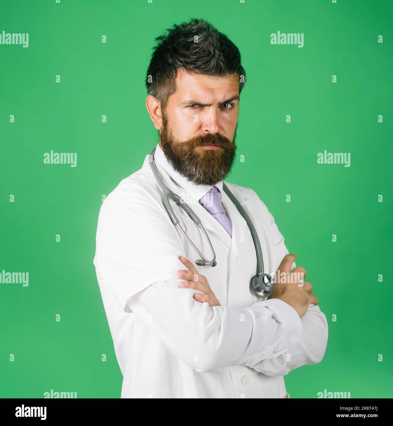 Seriöser Arzt in Arbeitskleidung mit gekreuzten Armen. Arzt im weißen Arztröbchen mit Stethoskop am Hals. Männlicher Arzt im Arztkleid mit gefalteten Armen. Stockfoto