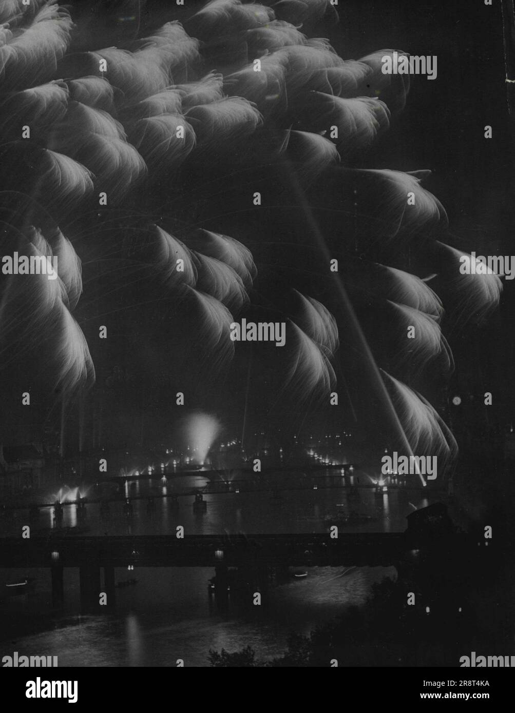 Victory Pageant am London River -- die Aussicht von der Spitze des Shell-Mex House. Fetzen von Akten erhellen den Fluss, während Suchlichter den Himmel erhellen. Die königliche Familie mit Tausenden von ihren Leuten kam zur Nacht, der Siegessnacht, zur größten Feuerwerkskörper und Suchscheinwerfer-Ausstellung auf dem Fluss zwischen den Brücken Hingerford und Vauxhall. 08. Juni 1946. (Foto von Reuterphoto). Stockfoto