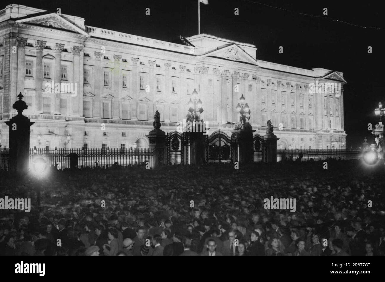 VJ Day in London -- der Buckingham Palace mit Flutlicht und die große, dicht gepackte Menge, die stundenlang davor stand und auf die Auftritte des Königs und der Königin wartete. Zur Feier des VJ Day wurden viele der berühmtesten Gebäude Londons mit Flutlicht beleuchtet und waren ein imposantes Spektakel. 15. August 1945. Stockfoto