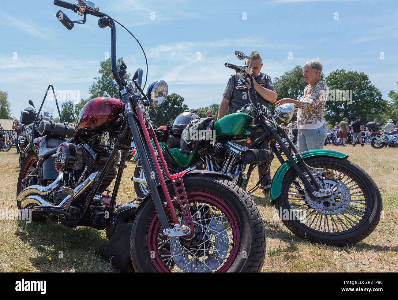 Leute, die bei einer Motorrad-Rallye über Motorräder diskutieren. Ein Mann und eine Frau unterhalten sich neben zwei leistungsstarken Motorrädern. Stockfoto