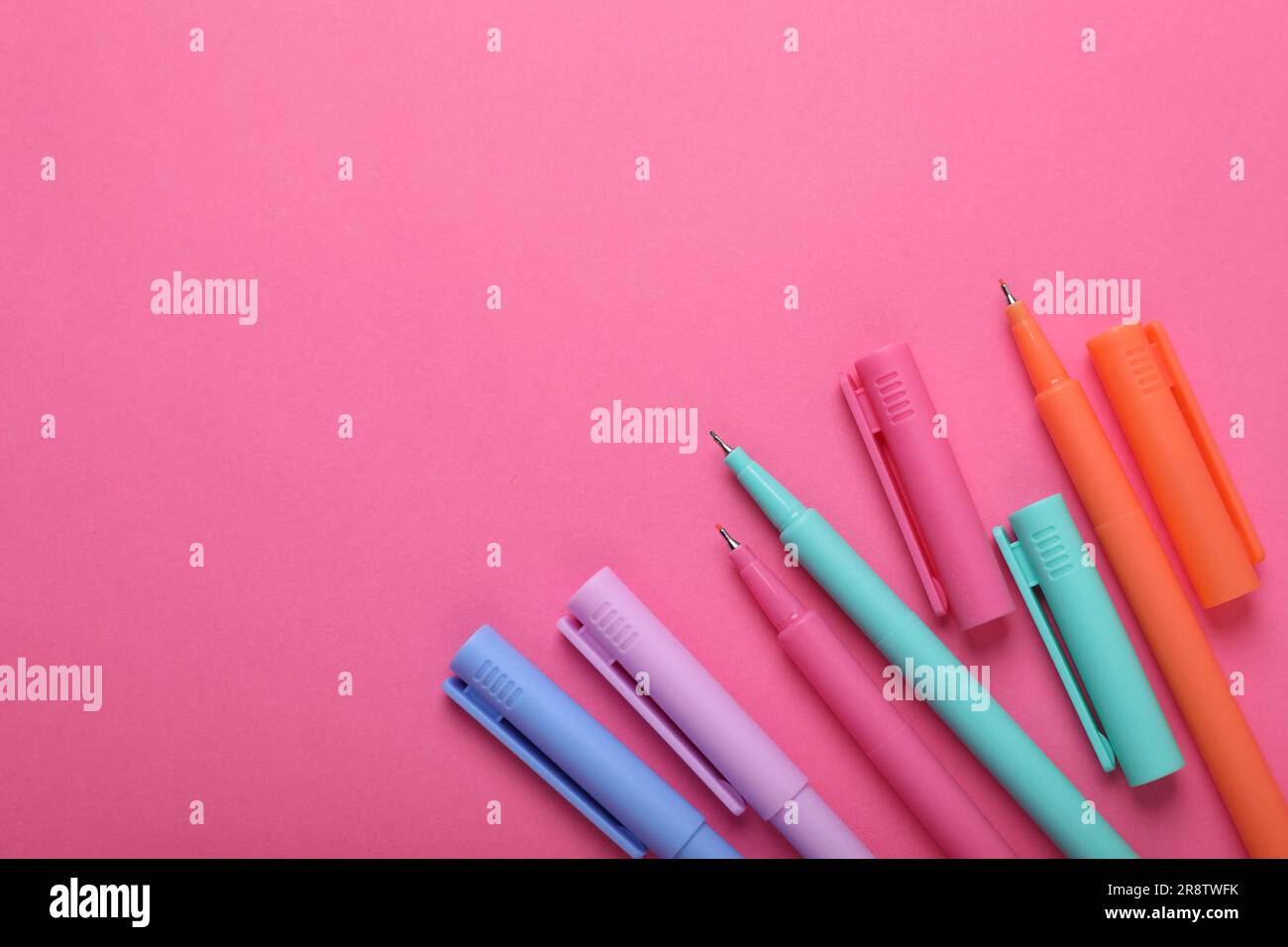 Viele bunte Marker auf pinkfarbenem Hintergrund, flach liegend. Platz für Text Stockfoto