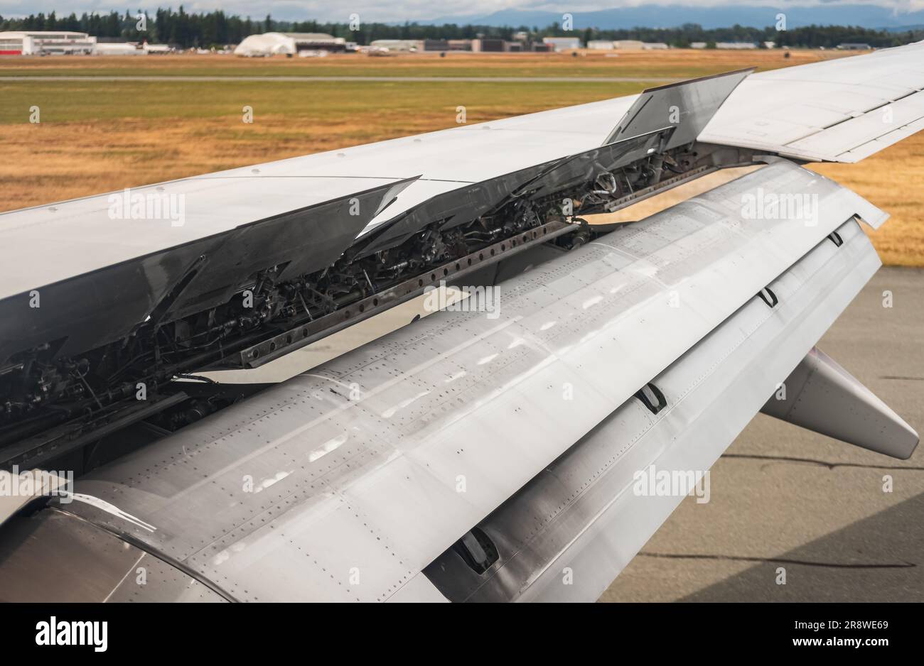 Landeflugzeug. Eine Fensteransicht des Flugzeugs auf Flügel und Klappen nach der Landung. Flugzeugflügel mit offenem Spoiler. Ein Reisefoto, niemand Stockfoto