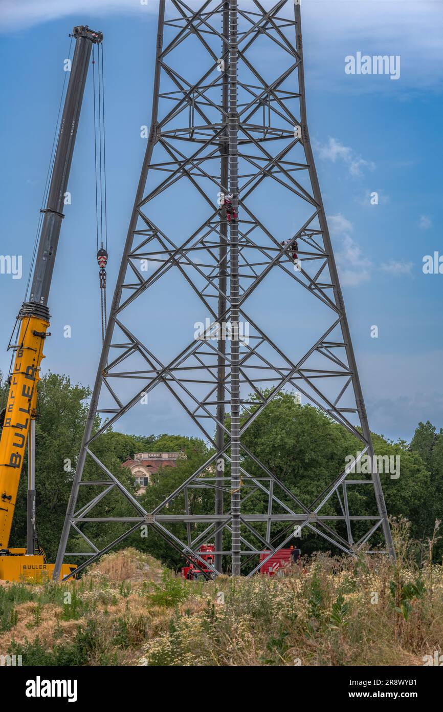 Arbeiter, die in großer Höhe einen Strommast zusammenbauen Stockfoto