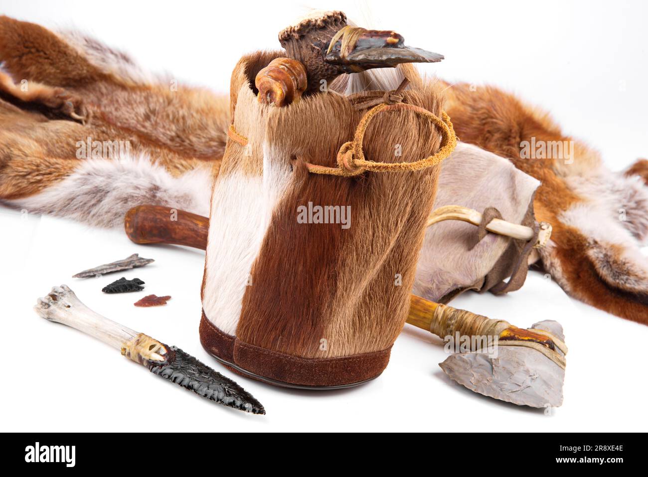 Steinzeit-Handtasche mit Cavemen Ax, Werkzeug und Messer auf weißem Hintergrund Stockfoto