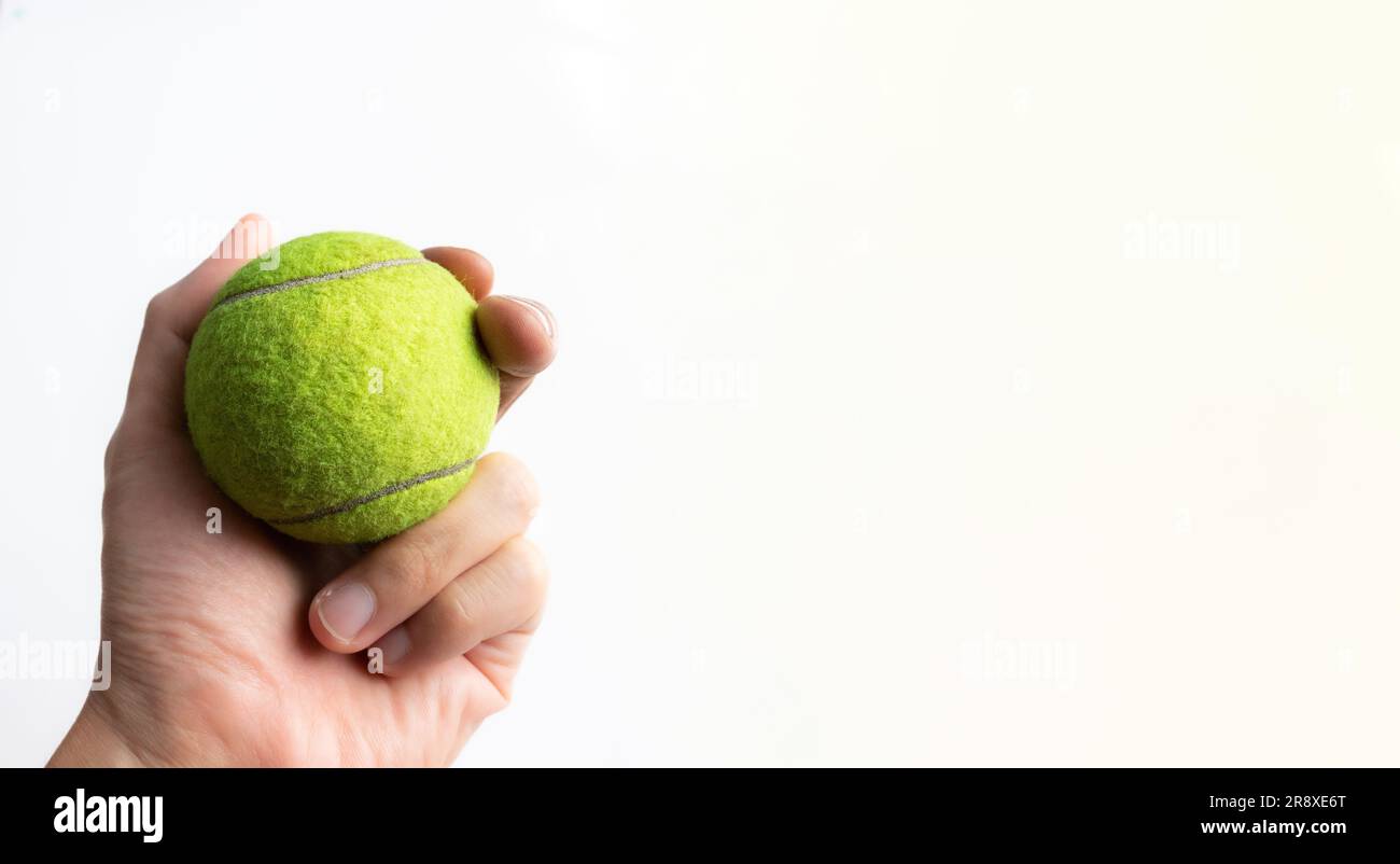 Die Hand hält einen Tennisball isoliert auf weißem Hintergrund. Nach einigen Bearbeitungen. Stockfoto
