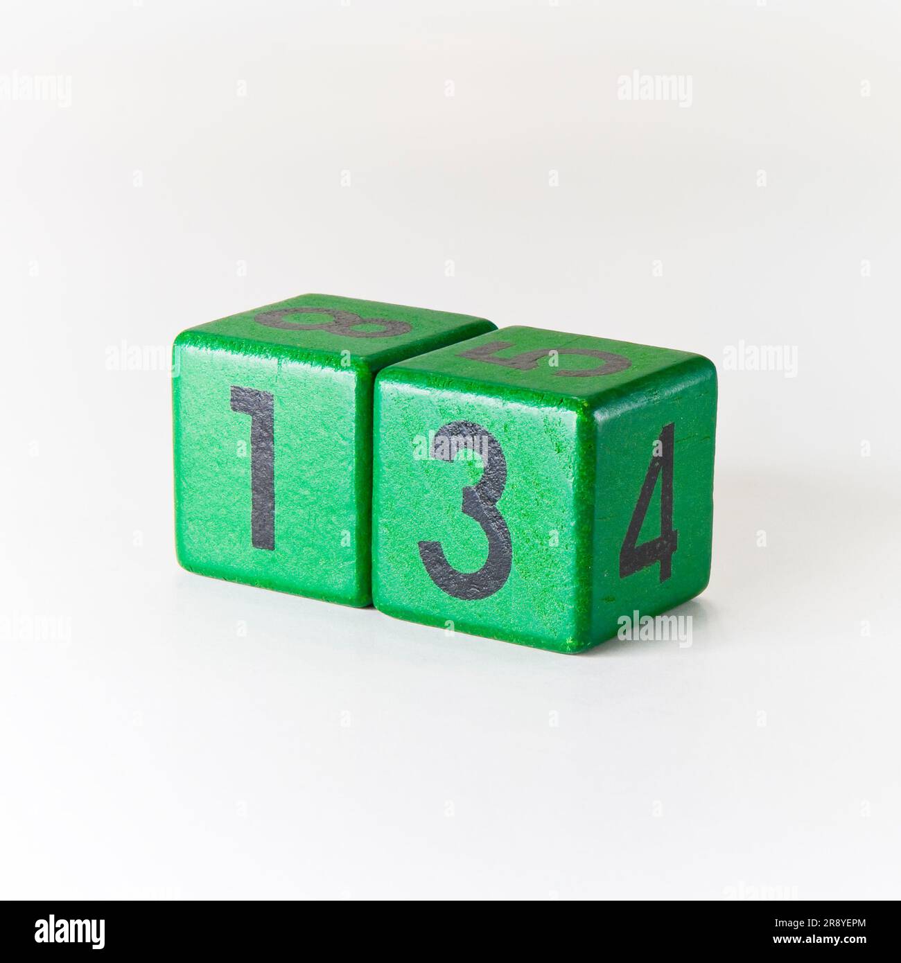 Nummer 13 auf einem hölzernen grünen Würfel auf weißem Hintergrund. Stockfoto