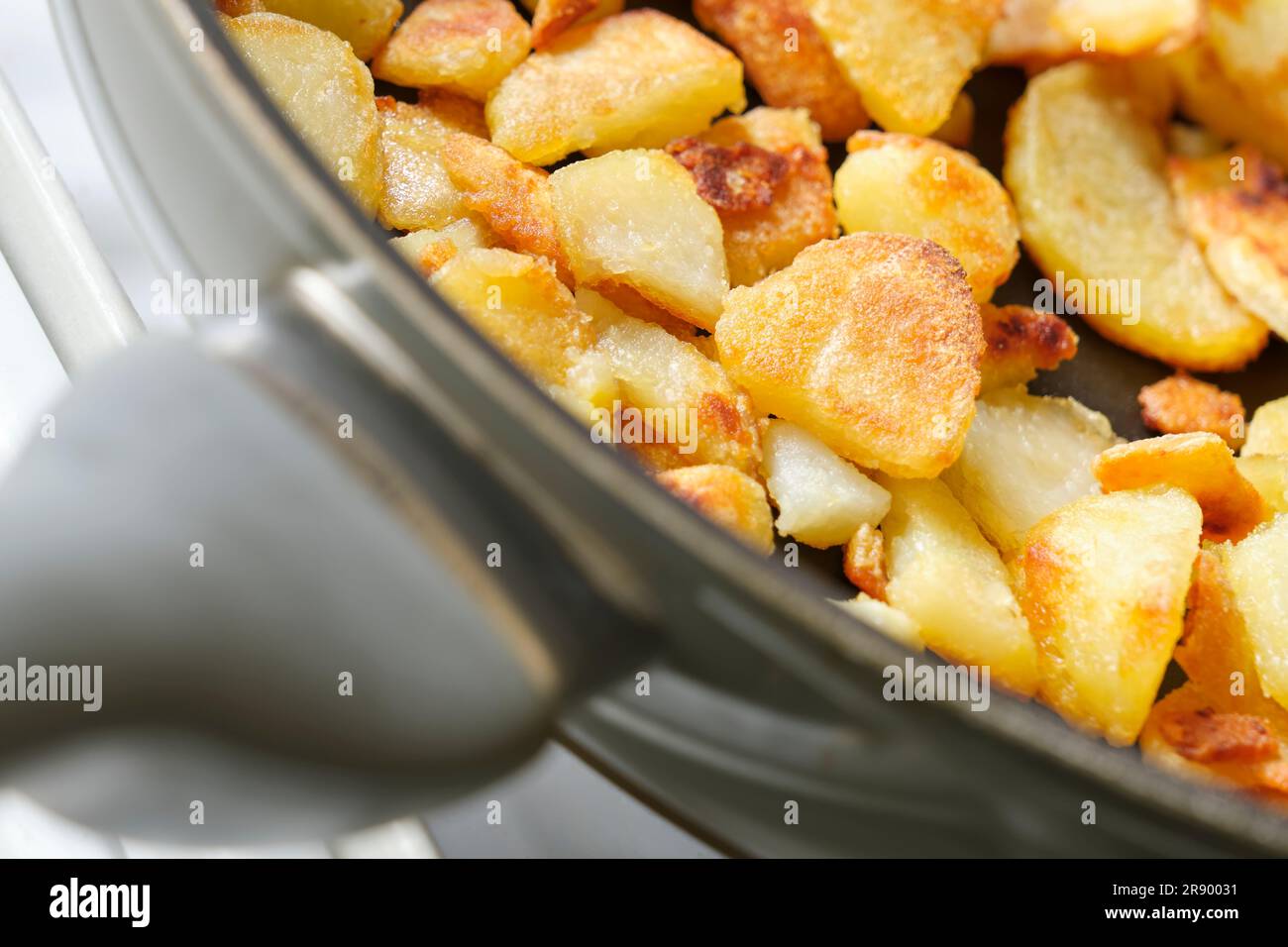 Eine kleine Portion gebratener oder gebackener gelber Kartoffeln mit knuspriger brauner Kruste in einer Pfanne. Bild mit selektivem Fokus. Stockfoto