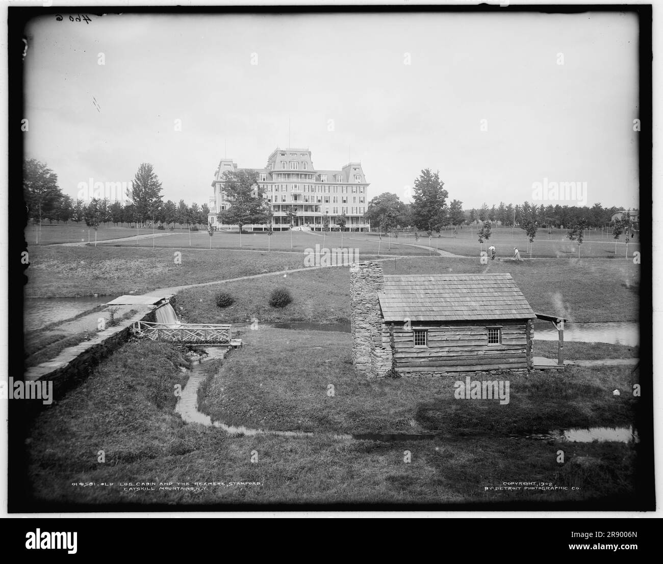 Alte Blockhütte und Rexmere, Stamford, Catskill Mountains, New York, c1902. Achten Sie auf eine hölzerne Fußgängerbrücke im Vordergrund und eine Frau, die rechts Golf spielt. Das Rexmere („King of the Meadow“) Hotel wurde 1898 eröffnet und brannte 2014 nieder. Stockfoto