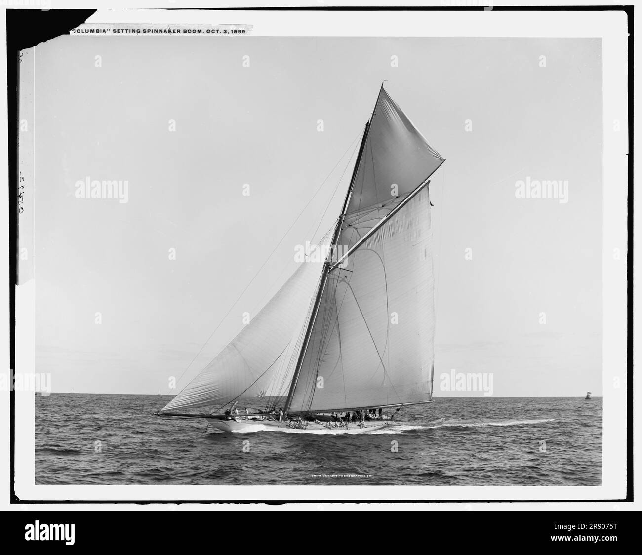 Columbia Setting Spinnaker Boom, 3., 1899., 1899. Okt. 3. Columbia war eine amerikanische Rennyacht, die 1898-99 von Nathanael Herreshoff und der Herreshoff Manufacturing Company für die Eigentümer J. Pierpont Morgan und Edwin Dennison Morgan vom New York Yacht Club entworfen und gebaut wurde. 1899 war sie Verteidigerin des zehnten America's Cup-Rennens gegen den britischen/irischen Herausforderer Shamrock. Stockfoto