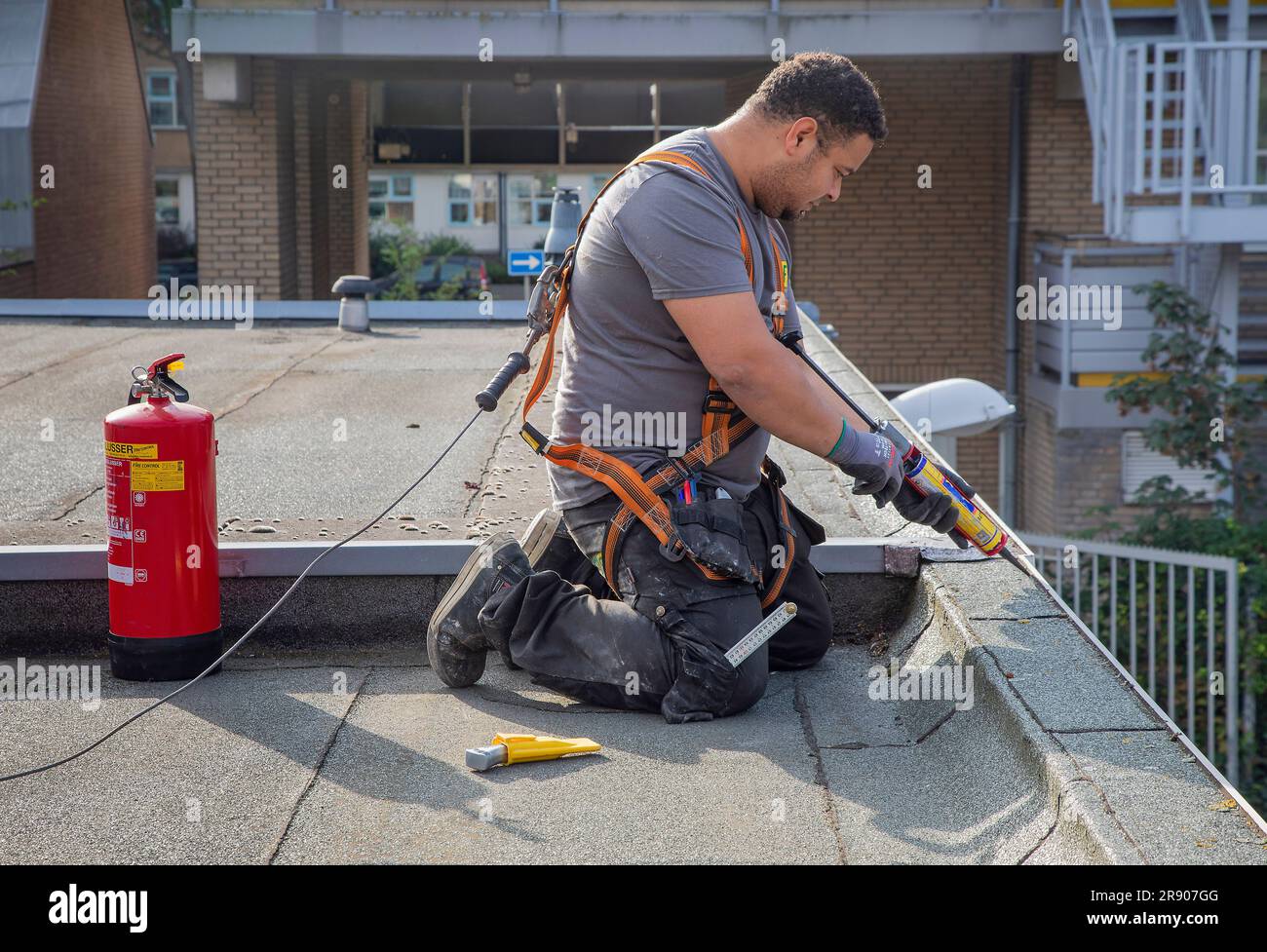 Niederlande, Den Haag; Klempner repariert einen Teil eines Dachs, während er mit einem speziellen harnas an einem Fallschutz-Schwerlastanker auf dem Dach befestigt ist. Stockfoto