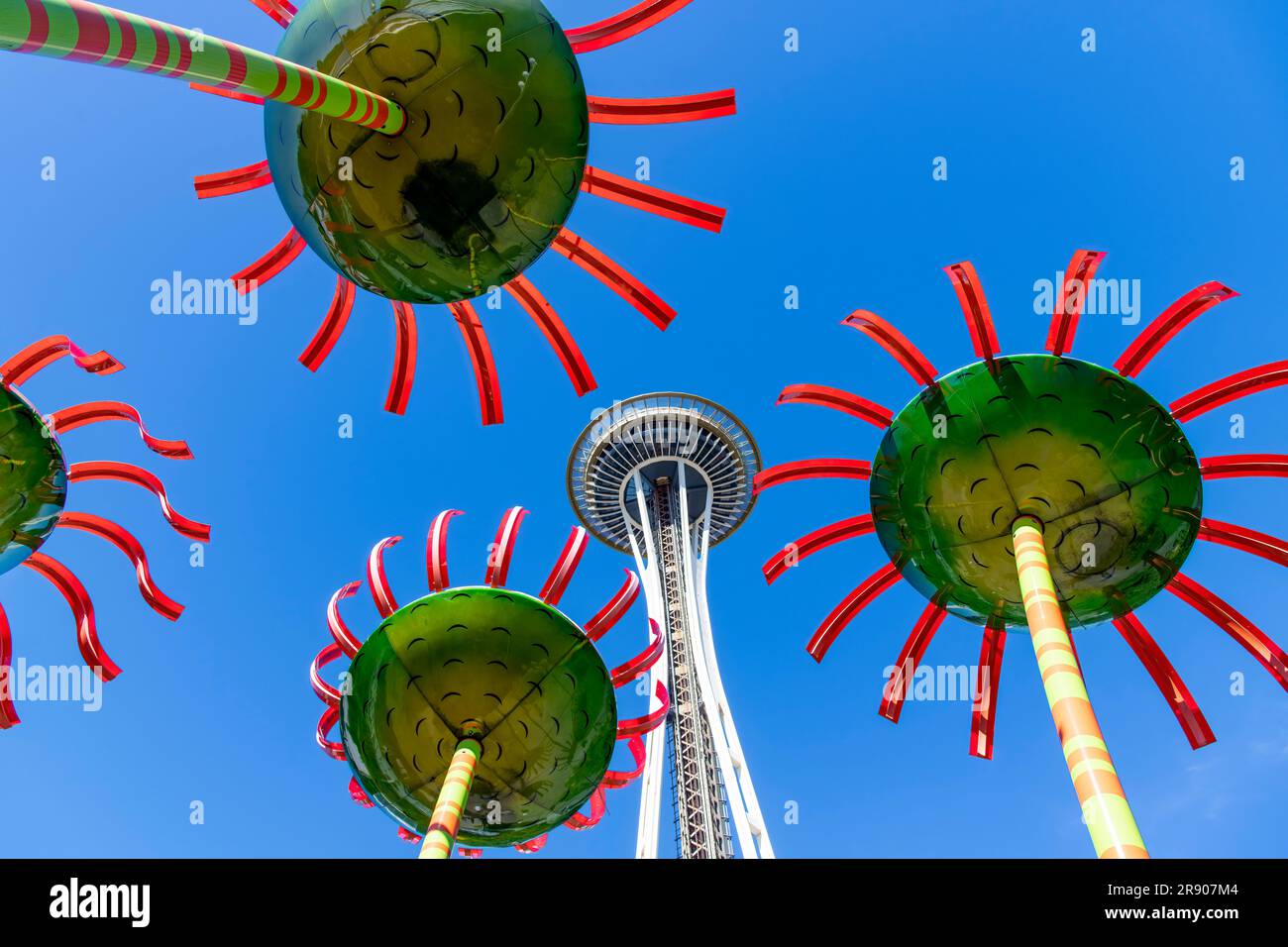 Seattle, WA, USA – Juli 2022; Low angle view of Space Needle Between Skulpture Sonic Bloom, ein Kunstwerk aus Stahl und Glasfaserblumen von Dan Corson at Stockfoto